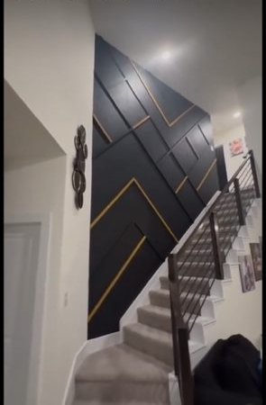 Staircase accent wall in dark panels with gold trim lines