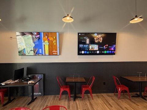 Two commercial TVs mounted in a restaurant dining room