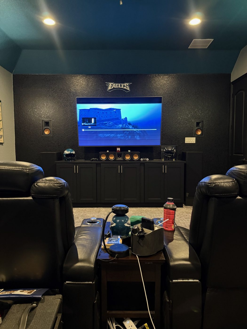 Home theater with mounted TV, cabinets, speakers and recliners